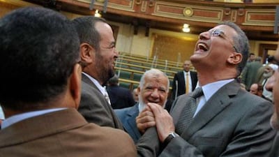 Egyptian members of parliament greet each other at a brief session of Parliament, the first since the country's high court ruled the chamber unconstitutional.
