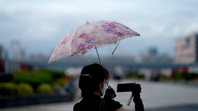 A woman takes a photo of the Tokyo skyline. Japan recently earned the dubious distinction of being one of only two advanced economies to have its growth outlook cut by the International Monetary Fund. Photo: AP