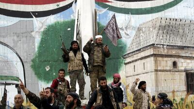 Rebel fighters, one of them carrying a flag used by Al Qaeda’s Nusra Front, celebrate at the Mihrab roundabout in the Idlib city centre on March 28, 2015. Khalil Ashawi / Reuters