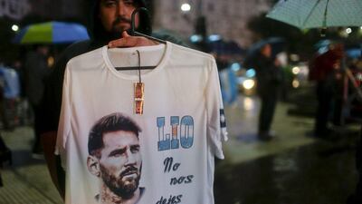 A vendor holds up a T-shirt that reads in Spanish “Lio don’t leave us”.