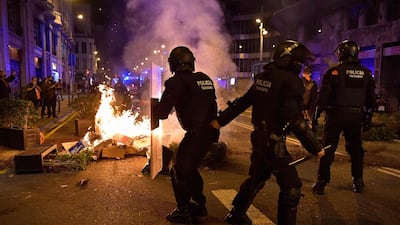 Members of the Catalan regional police force Mossos d'Esquadra take position next to burning trash set on fire by protesters. AFP