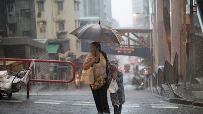 A woman and a child in raincoat try to shelter from heavy rains while crossing a street in Hong Kong. The Hong Kong Observatory issued a Black rainstorm warning on Wednesday. Jerome Favre / EPA