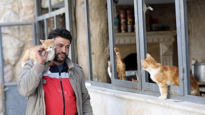Mohammed Alaa al-Jaleel carries a cat on his shoulder at Ernesto's Cat Sanctuary that he runs in Kfar Naha, an opposition-held town in Aleppo province. AFP