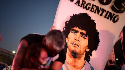 A father and daughter mourn as they gather by the Buenos Aires Obelisk to pay homage to Maradona. AFP