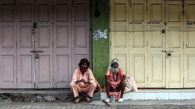 Indian sadhus or holy men sit in front of closed shops on the roadside on the banks of Godavari river. Divyakany Solanki / EPA
