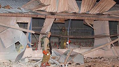 Israeli soldiers survey the damage after a rocket fired from Lebanon hit a gas tank in the town of Netua last night in the yesterday.