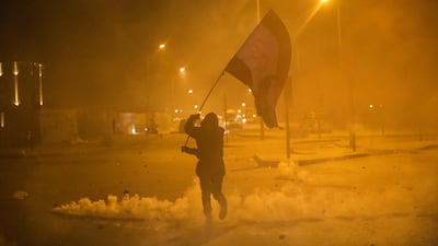 An anti-government protester holds a Lebanese flag during clashes with riot police in Beirut, Lebanon. Getty Images