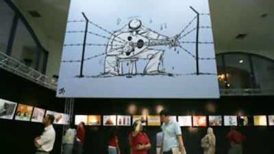 Jordanians view Emad Hajjaj's cartoons at an exhibition of his work in Amman.
