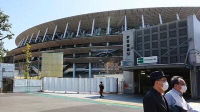 People walk past at the National Stadium in Tokyo on March 10, 2021. AP