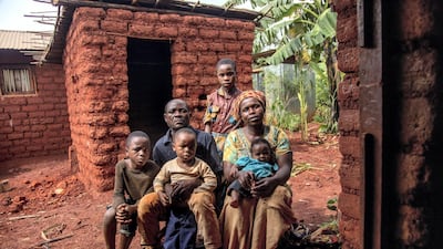 Burundian refugee Nyamoza Rachel, 24, sits with her husband and children outside her kitchen that was built to house a new stove design for refugees in Nyarugusu camp. Georgina Goodwin / UNHCR