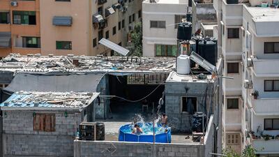 Members of a Palestinian family cool off together in the water in a metal frame pool erected on the rooftop of a residential building in Gaza City. AFP