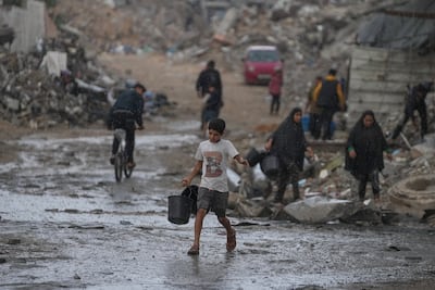 A boy carries two empty buckets on his way to collect water amid a rainstorm in the Sheikh Radwan neighbourhood of Gaza. AP