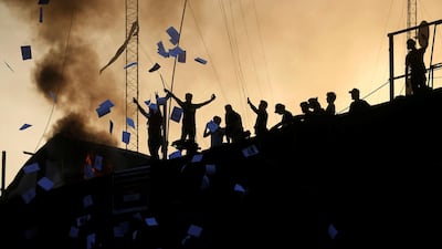 Protesters throw documents as they stand on concrete blast walls. Reuters