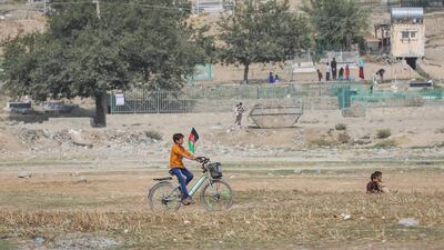 A boy carries an Afghanistan national flag as he rides his bicycle on Independence Day in Kabul, Afghanistan. EPA