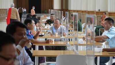 Members of Myanmar's parliament are pictured on a break abiding by social distancing rules with plastic dividers at tables at the Pyidaungsu Hluttaw parliament building in Naypyidaw. AFP