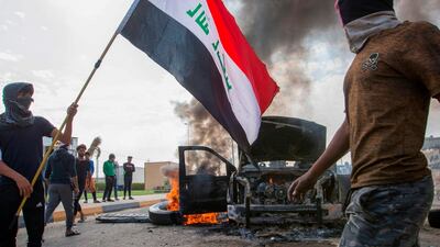 Iraqi demonstrators stand next to the smoking remains of an Iraqi anti-riot vehicle during a demonstration in the southern city of Basra. AFP