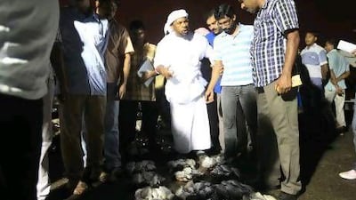 An Emirati auctioneer leads a group of quiet buyers around the small piles of fish laid out in lots.