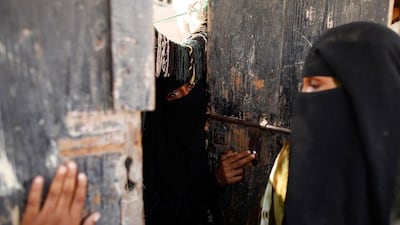 Women stand by the door of their hut.
