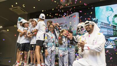 Ahmed Al Kaabi of Abu Dhabi Motorsport Management looks on as the boys of Team Eagle Eye and the girls of Team Turbo Squad celebrate their achievements in the Formula Ethara competition at Yas Marina Circuit. Antonie Robertson / The National