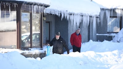 Residents stand outside a house which has been snowed in. Getty Images