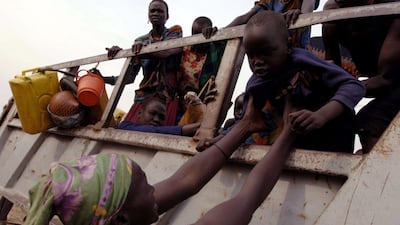 A Dinka mother, from a group who fled Bor, Upper Nile region some 13 years ago, carries her child from a truck as the first Dinka cattle herders, mainly vulnerable elderly, sick, women and children arrive in Juba, southern Sudan at a transit facility supported by UN agencies and NGO's in this picture released by UNICEF December 1, 2005. Reuters