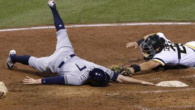 Milwaukee Brewers’ Jake Elmore (7) reaches to touch home plate after sliding around the tag by Pittsburgh Pirates catcher Francisco Cervelli during the eighth inning of a baseball game in Pittsburgh. Elmore was called safe, the Pirates challenged, and safe call stood. The Brewers won 7-4. Gene J. Puskar / AP Photo
