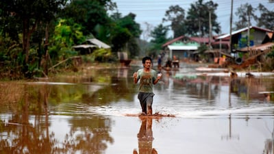 A man wades through a flooded road at a village in Sanamxai, Attapeu province. AFP
