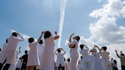 Medical workers react as they watch the Blue-Impulse aerobatic team of Japan Air Self-Defense Force fly over the Self-Defense Forces Central Hospital in Tokyo, Japan. Reuters