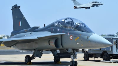 A French Rafale fighter flies over an Indian Airforce Tejas jet with Bipin Rawat, the 27th chief of army staff of the Indian Army on board in the co-pilot's seat before take-off during the Aero India air show at Yelahanka Air Force base in Bangalore.