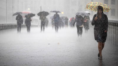 People cross London Bridge during heavy rainfall. The British Met Office has warned of widespread flash floods with thunderstorms likely across the country. EPA