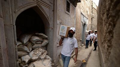 Volunteers wearing masks deliver food parcels to households in Mosul. Covid-19 has increased hardship for many people. AFP