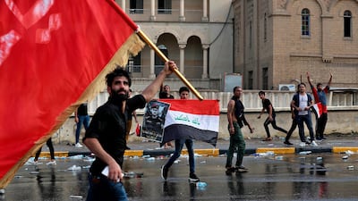 Protestors wave flags and hold a poster of Lt Gen Abdul Wahab Al Saadi during a protest in Baghdad, Iraq. AP Photo