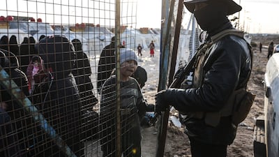 Syrian internal security forces stand guard along the fence of Al-Hol camp in the desert region of Syria's Hasakeh province on January 21, 2026. Syria's army entered the vast Al-Hol camp that houses relatives of suspected Islamic State jihadists after Kurdish forces withdrew from the site, said an AFP journalist at the scene. The camp in a desert region of Hasakeh province holds around 24,000 people, including some 6,200 women and children from around 40 nationalities. (Photo by OMAR HAJ KADOUR / AFP)