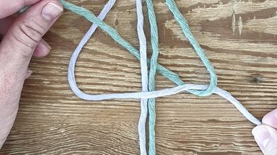 Bring the right knotting rope to the left side by going behind the two centre filler cords and through the four-shaped loop made by the first left knotting cords.