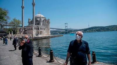 Elderly people wearing protective face masks, stroll along the seaside on May 10, 2020, at Ortakoy in Istanbul. AFP
