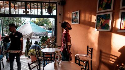 Eritrean painter Noah Mulubrhan 35, (R) looks at hanged paintings as he prepares an exhibition in a local coffee shop in Addis Ababa. AFP