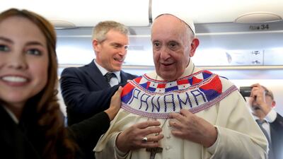 Pope Francis wears a Panama banner as he meets journalists onboard the plane taking them to Panama City. Reuters