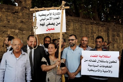 Former inmates of Khiam prison hold placards in Arabic that read, "who listens to the American administration and the Israeli enemy. He is an agent," left, and "the independence of justice is when the judiciary is independent from American political and security pressures," right, during a sit-in near a military court where an arrest warrant was issued for Lebanese-American Amer Fakhoury. He confessed he'd worked for Israel during its occupation of Lebanon for nearly two decades. AP