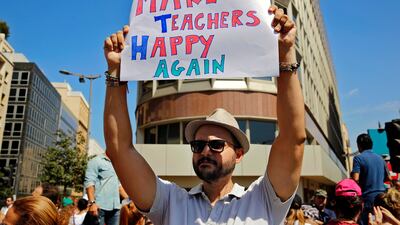 A protester holds up a placard during a rally in front of the government building in downtown Beirut on September 26, 2017. Lebanon's civil servants are on strike to pressure the government to pay them recently approved wage hikes amid a new crisis over how to finance the bill. Bilal Hussein / AP