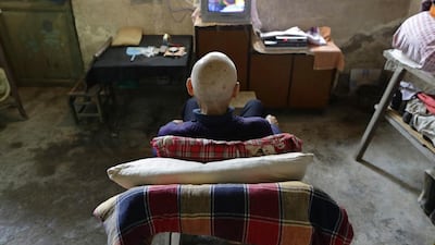 Qin Wenji, 82, who suffers from skin cancer, watches TV in his bedroom at Heshan village. Jason Lee / Reuters