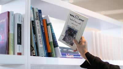 Participants are encouraged to donate a book from a table in the exhibition and place it on the shelf in exchange for a white book. Photo: Reem Mohammed/The National