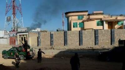 Afghan security forces stand guard as smoke rises from the entrance gate of the presidential palace in Kabul.