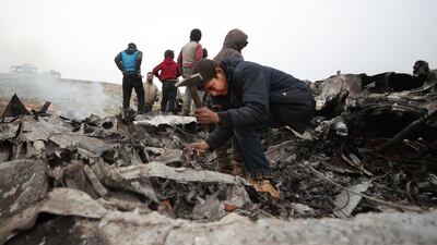Children search for scrapes of metal among the debris of a Syrian military helicopter that was shot down on February 14, 2020, in the western countryside of Aleppo province. AFP