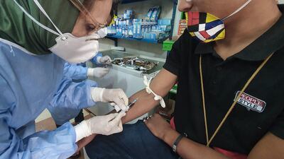 A Libyan doctor takes blood sample from a shopkeeper to test for the coronavirus in the Tajura area, a coastal suburb east of the capital Tripoli. AFP