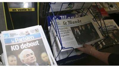 A woman picks up a copy of a newspaper headlining on the IMF chief Dominique Strauss-Kahn's arrest.