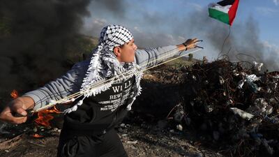 A Palestinian protester hurls a rock at Israeli security forces during clashes near Shejaiya, an eastern district of Gaza City along the border with Israel. Mahmud Hams / AFP
