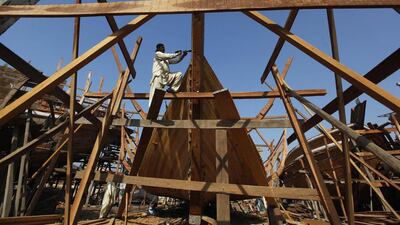 A carpenter uses manual tools to cut out a wood panel while working on a boat at a yard in Karachi's Fish Harbour. Akhtar Soomro / Reuters