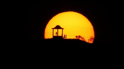 People are silhouetted against the setting sun at "El Mirador de la Alemana" as the summer's second heatwave hits Spain, in Malaga. Reuters