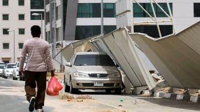 A man walks past a construction fence that was toppled by a storm that hit Silicon Oasis in Dubai.