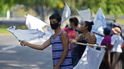 People flutter improvised white flags along a road to show their need for food during a mandatory quarantine imposed by the government against the spread of the new coronavirus in San Pedro Perulapan, El Salvador. AFP